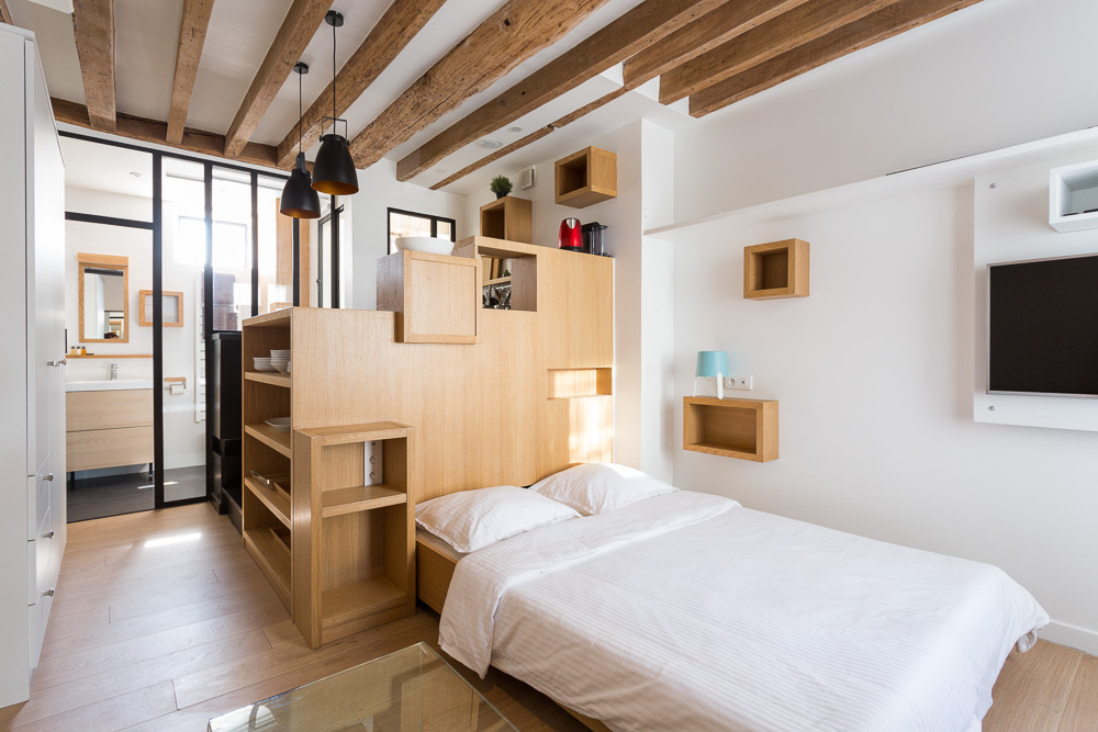 Studio lumineux sous poutres, lit double et rangements en bois clair