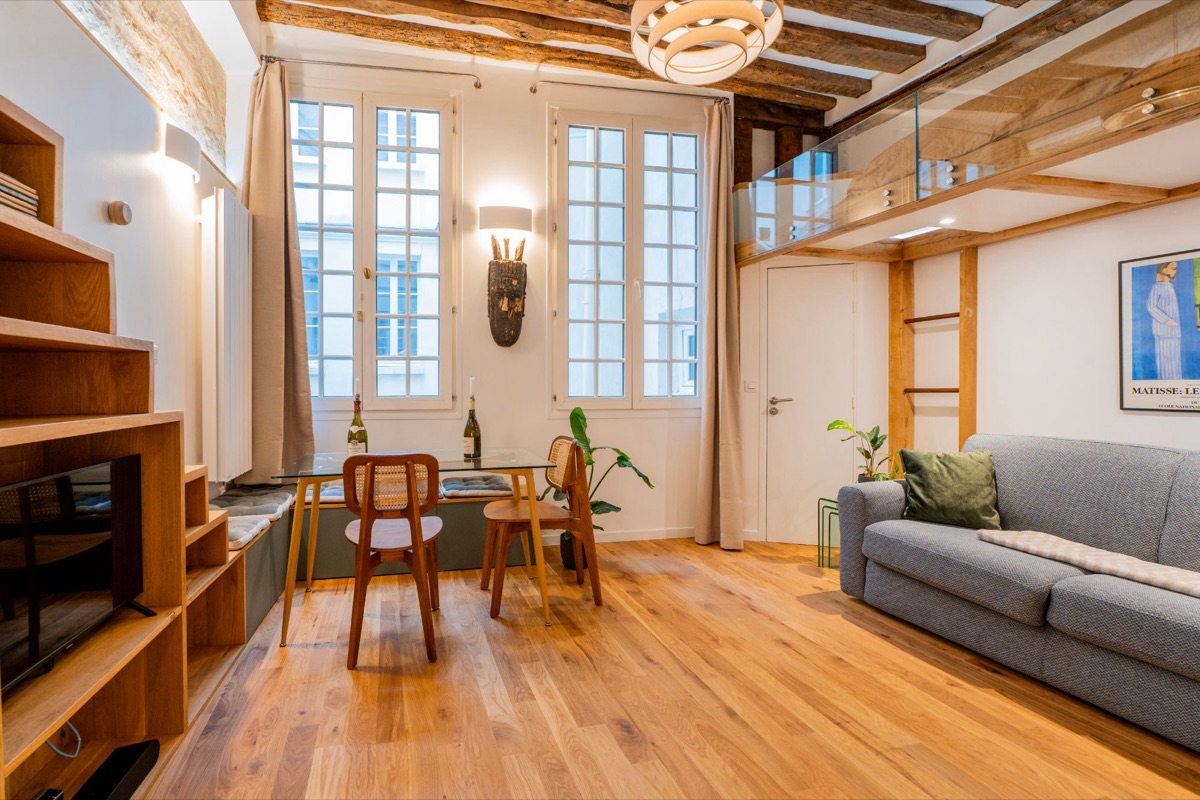 Séjour sous poutres avec mezzanine vitrée, parquet en chêne et canapé